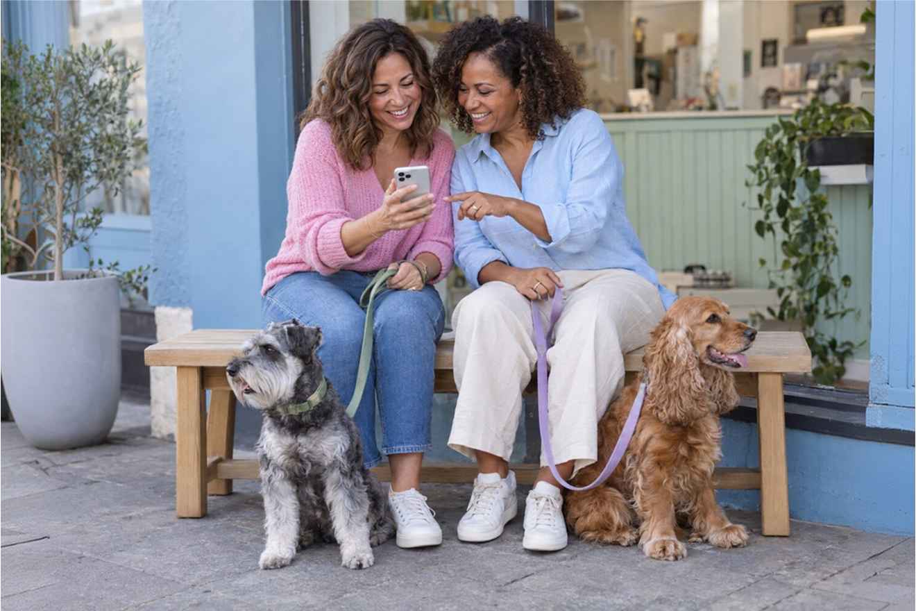 Pet owners using phones beside their dogs
