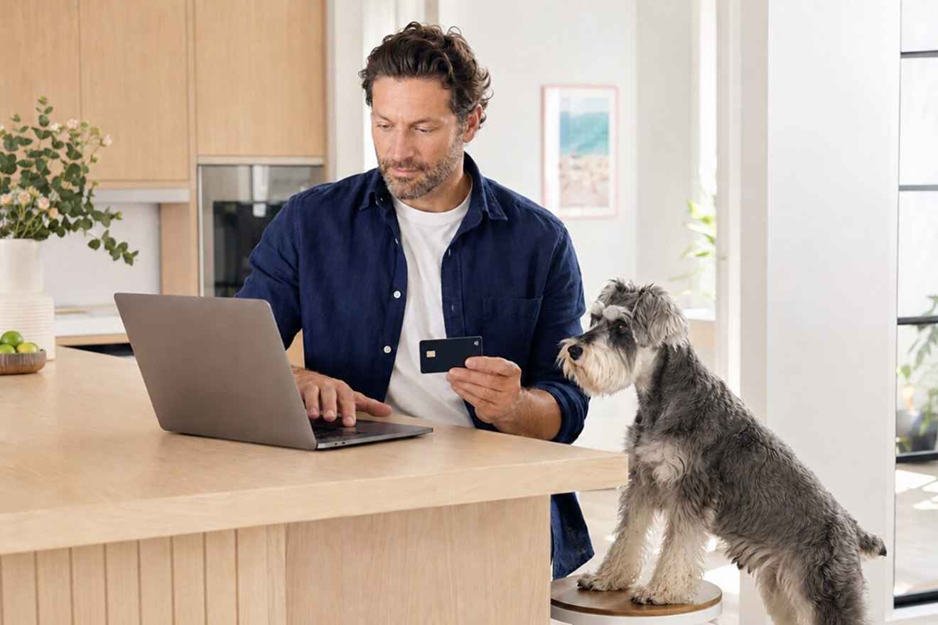 Pet owner buying a gift card online beside a dog