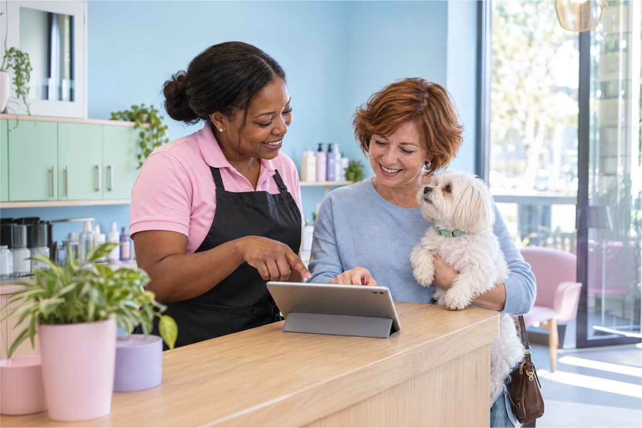Pet business staff checking a tablet beside a dog